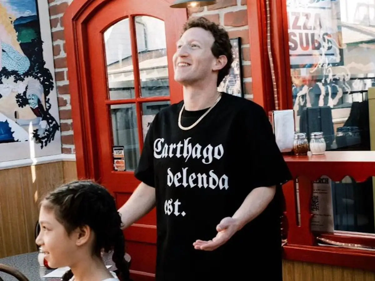 Man wearing a black t-shirt with text in a casual setting, possibly a cafe or restaurant within roman empire and Karthago